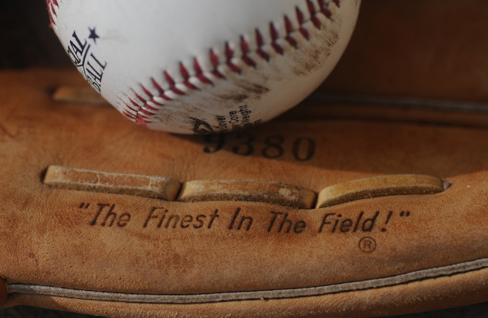 Pelota de béisbol blanca y roja sobre mesa de madera marrón