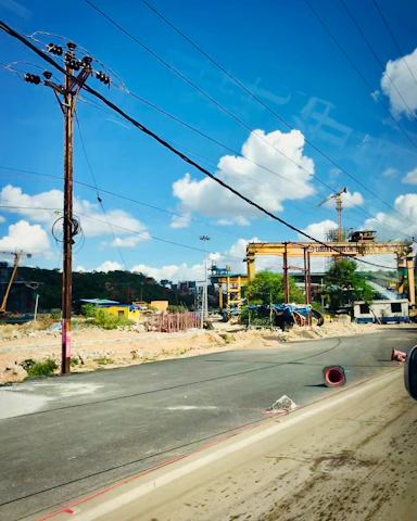 A team of engineers reviewing blueprints on a construction site with heavy machinery and solar panels in the background.