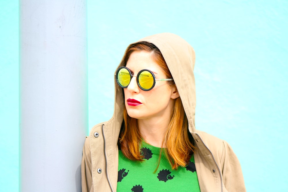 woman in brown coat wearing green shirt and brown sunglasses