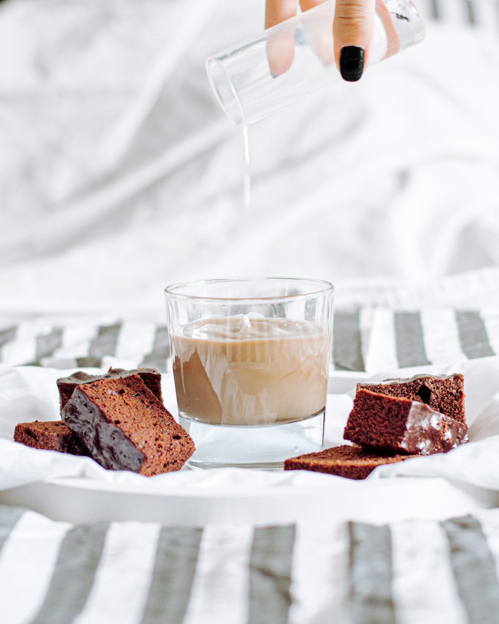 clear drinking glass with brown liquid on white ceramic plate