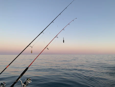 Fishing rod bent against the blue ocean during a fight