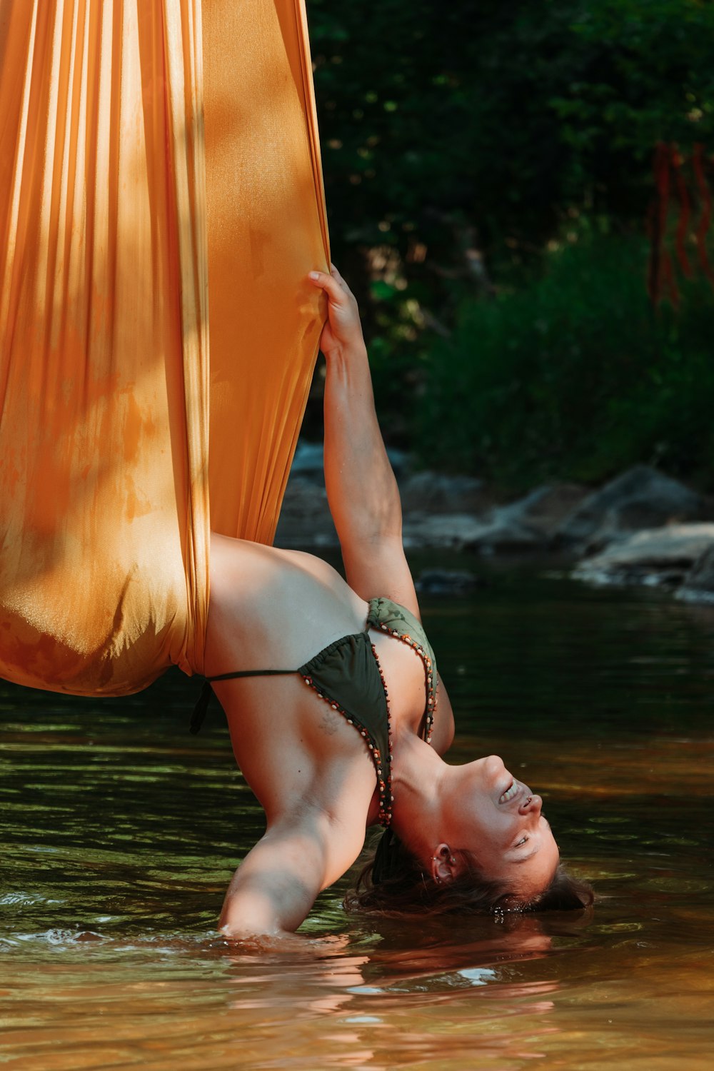 woman in black bikini lying on orange hammock