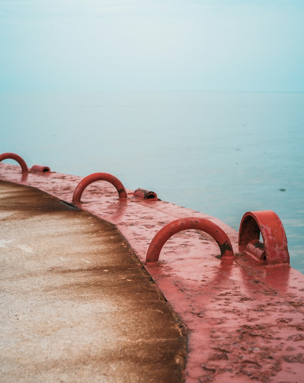 red metal pipe on brown wooden dock during daytime
