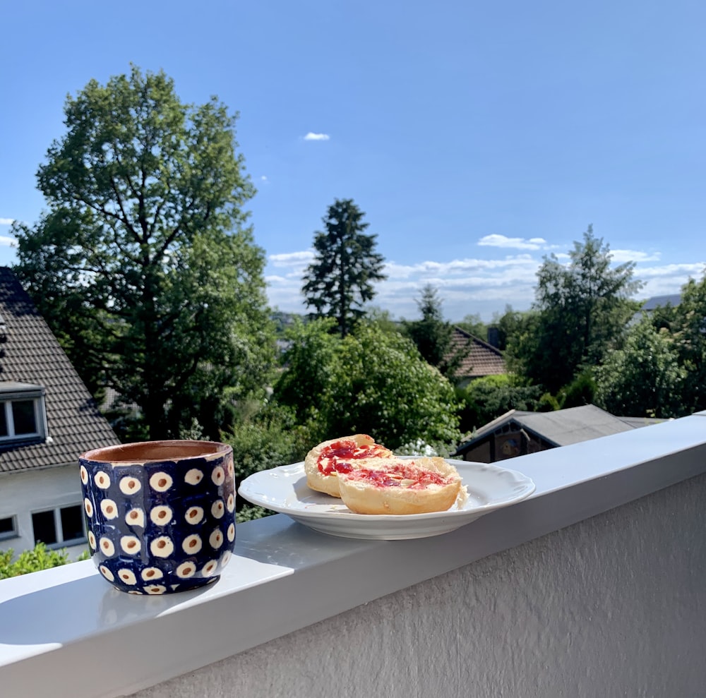 Tasse en céramique blanche et noire à côté d’une assiette en céramique blanche sur une table blanche