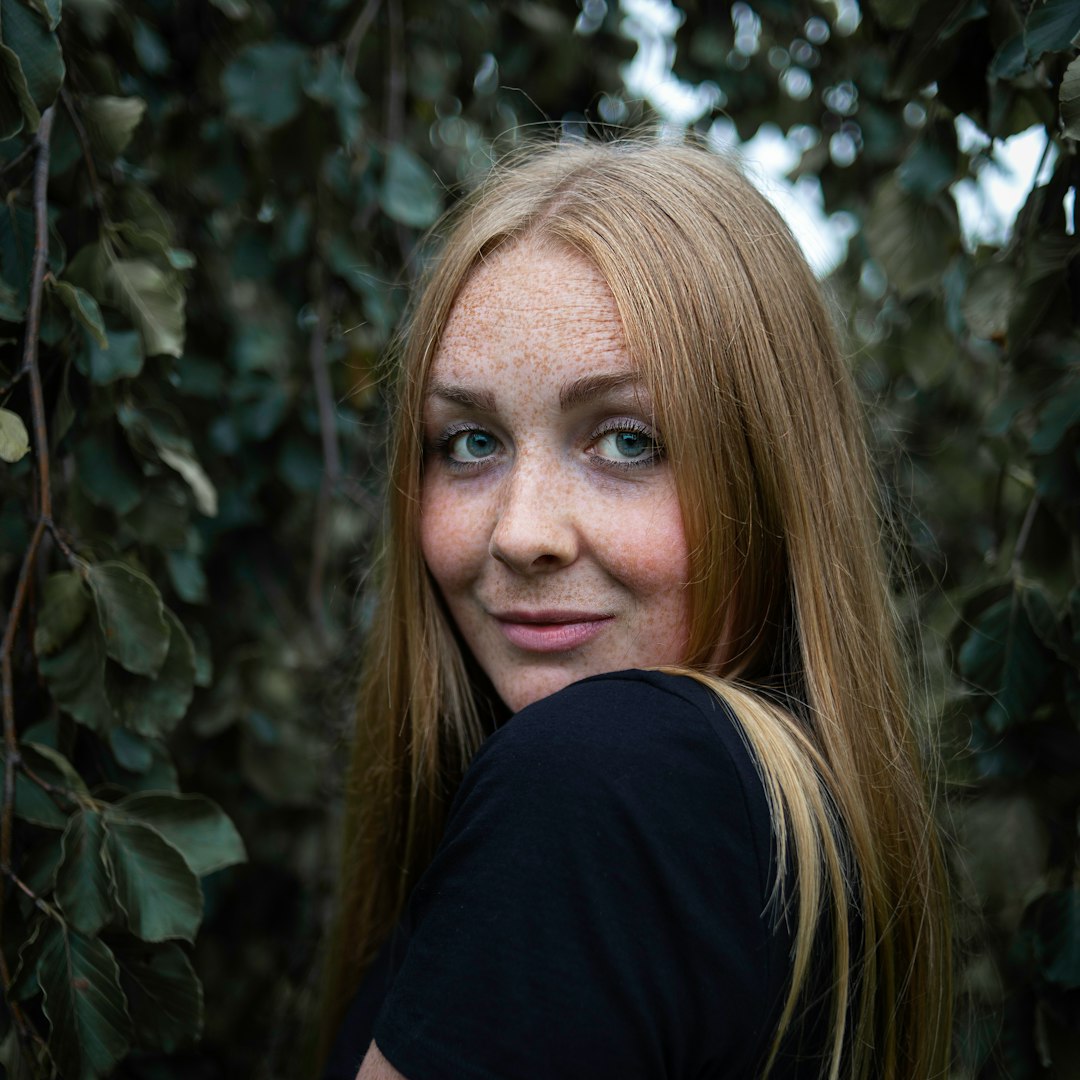 woman in black shirt standing near green plant