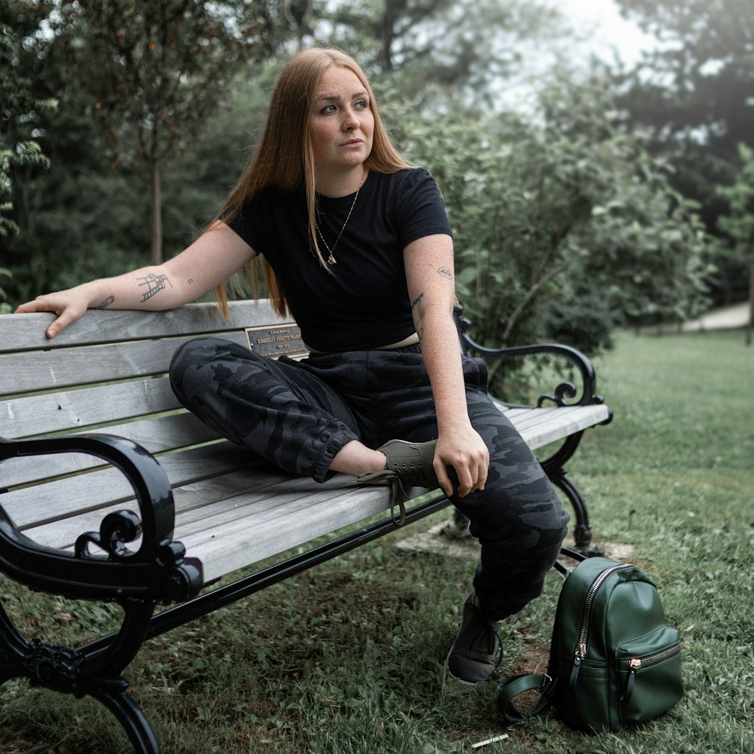 woman in black shirt and black pants sitting on black wooden bench