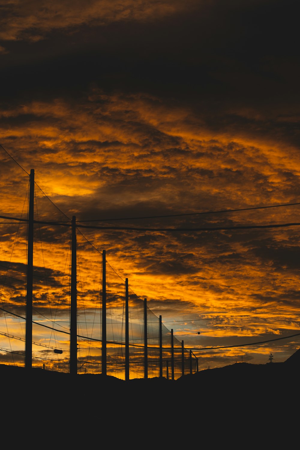 black metal electric posts under white clouds and blue sky during daytime