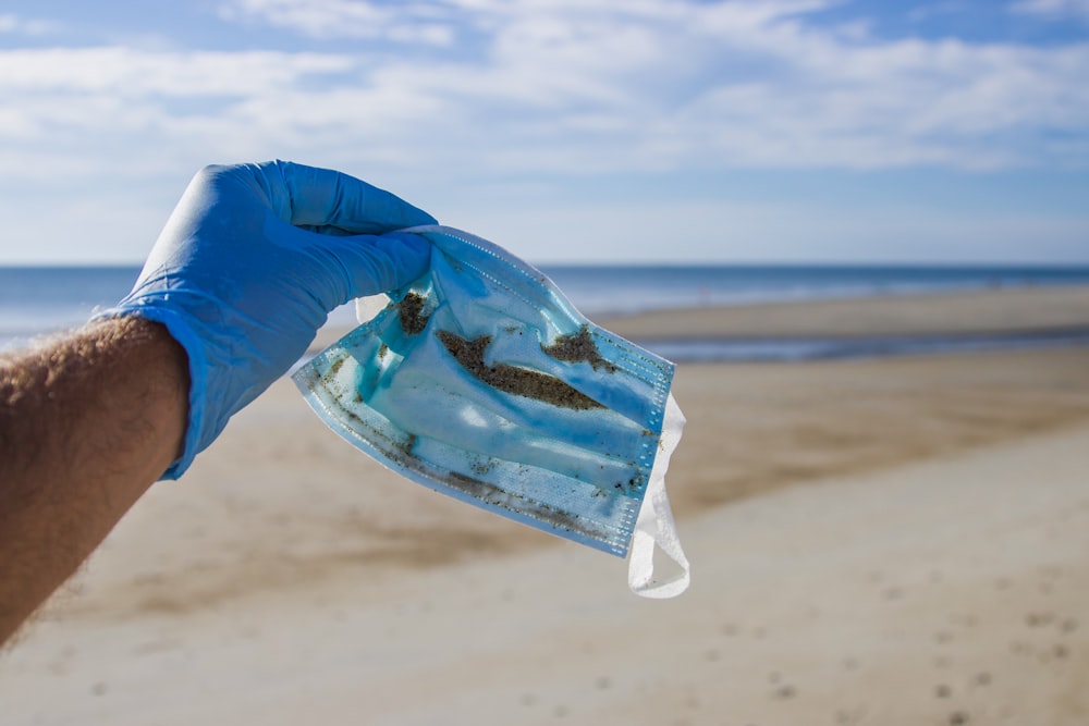 Personne en chemise bleue à manches longues et pantalon bleu debout sur la plage pendant la journée