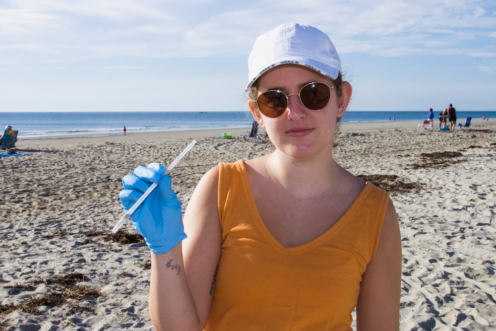 Mujer con camiseta sin mangas morada con gorra blanca y gafas de sol
