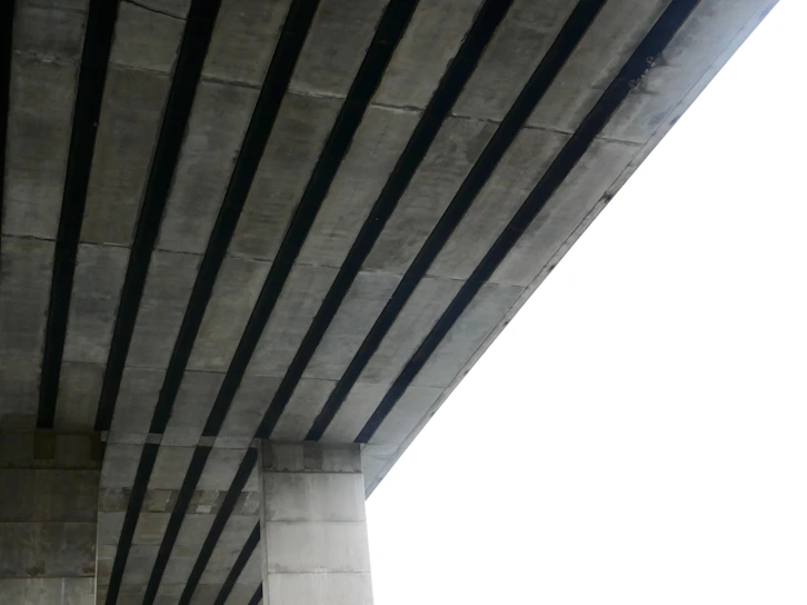 A detailed view of a precast concrete pile being installed at a bridge foundation site.