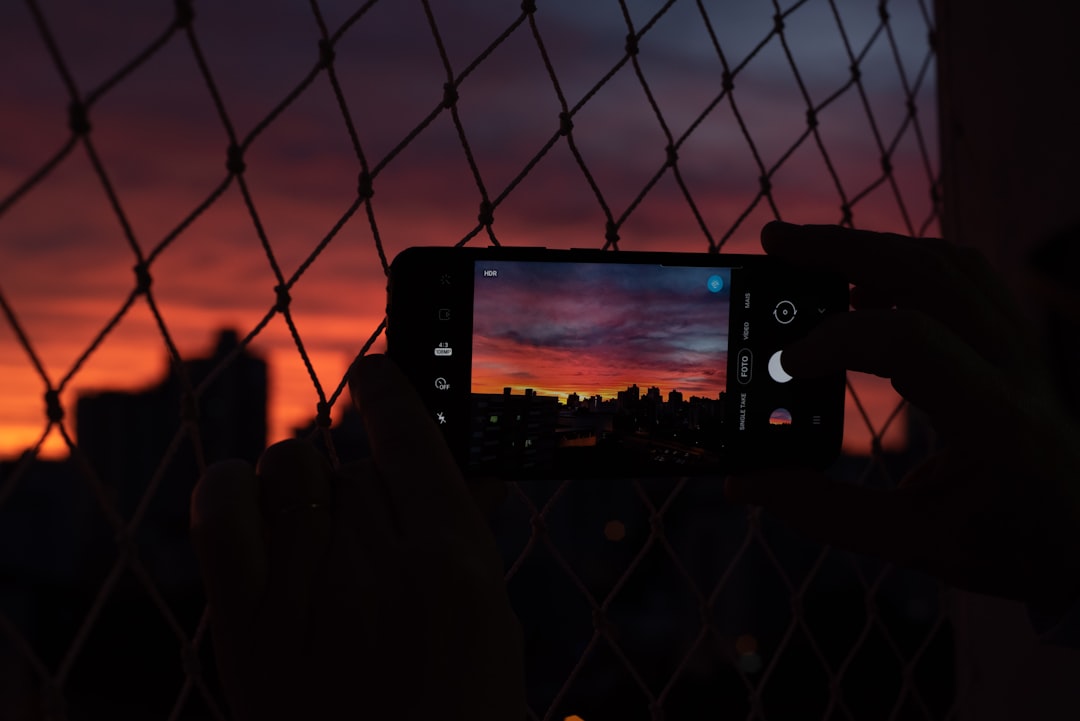 person taking photo of city skyline during night time
