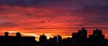 Balcony view from a hotel room showing a vibrant sunset over a bustling cityscape.