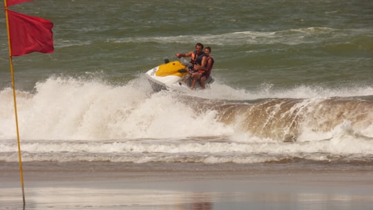 man in black shorts riding yellow and white surfboard on sea waves during daytime in Pinamar Argentina