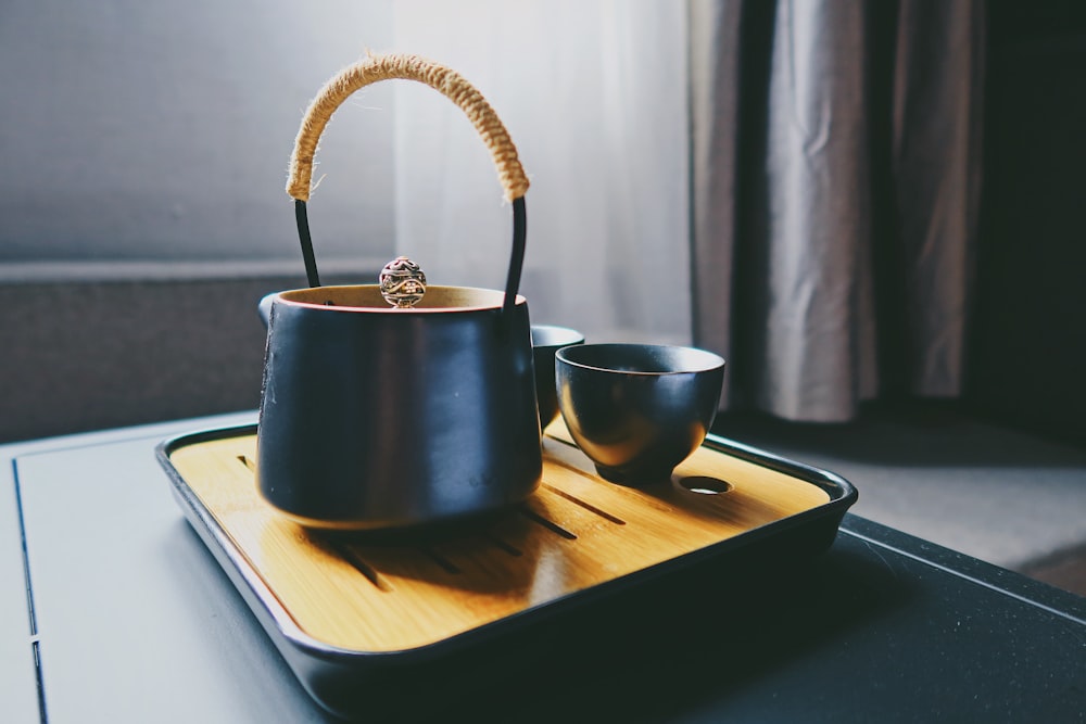 black ceramic teapot on brown wooden tray