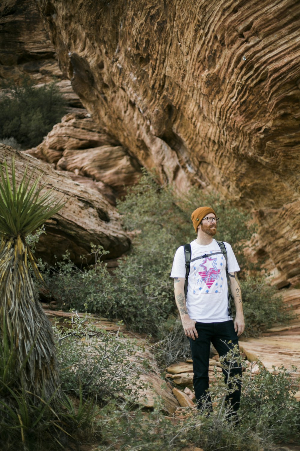 woman in white crew neck t-shirt standing beside brown rock formation during daytime