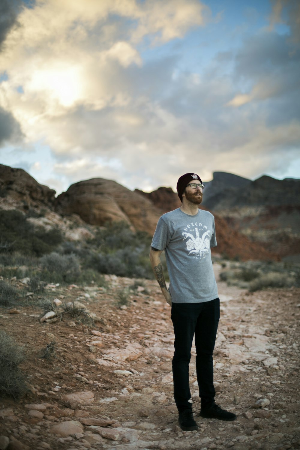 man in white crew neck t-shirt and black pants standing on brown field during daytime