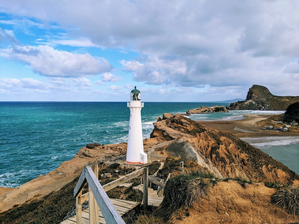 farol branco perto do corpo de água durante o dia