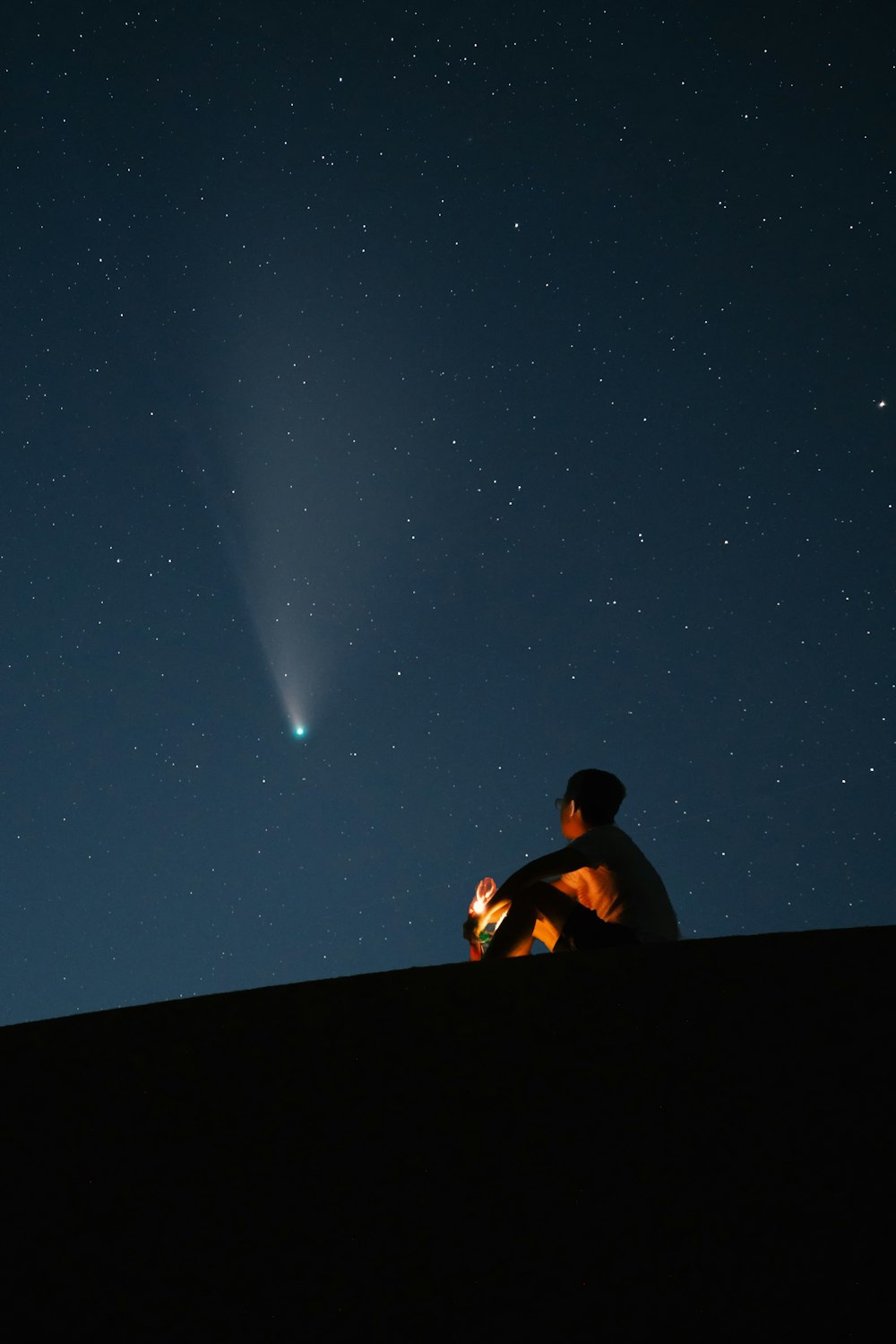 星空の下で黒い椅子に座る黒いシャツの男