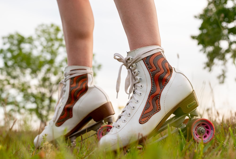 Person in weißen Converse All Star High Top Sneakers, die tagsüber auf grünem Gras stehen