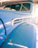 Close-up of a vintage car's polished chrome details shining under indoor lighting.