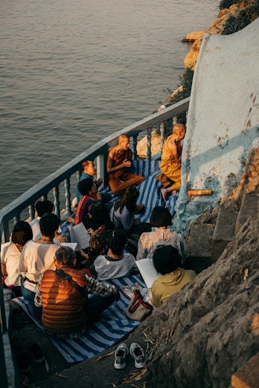 A serene group meditating at sunrise on the ghats of Varanasi, with the river gently flowing beside them.