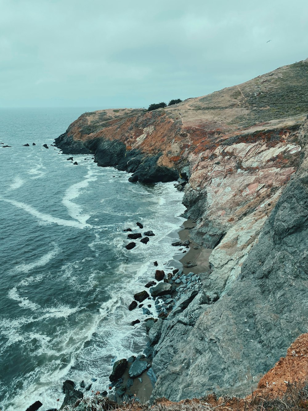 rocky shore with sea waves crashing on rocks during daytime