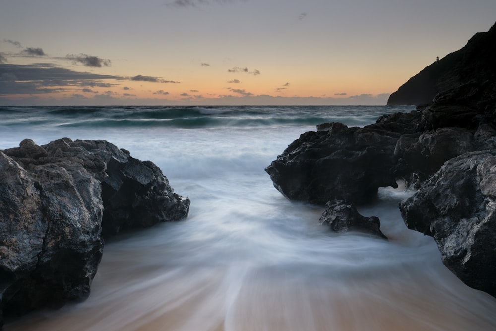 black rock formation on sea during daytime