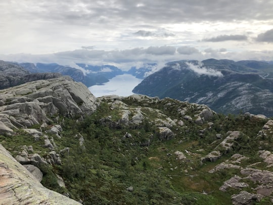 green and brown mountains under white clouds during daytime in Prekestolen Norway