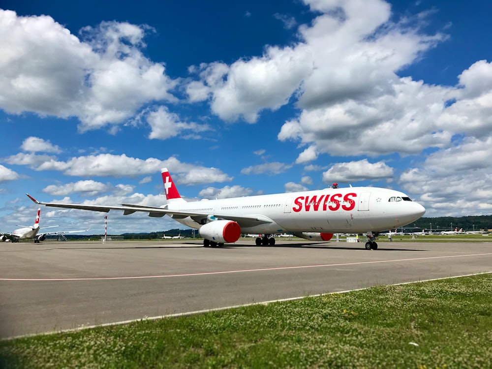 white and red passenger plane on airport during daytime