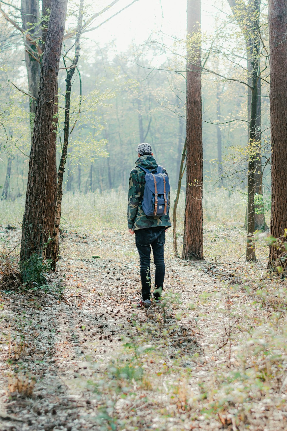 Mann in schwarzer Jacke geht tagsüber durch den Wald
