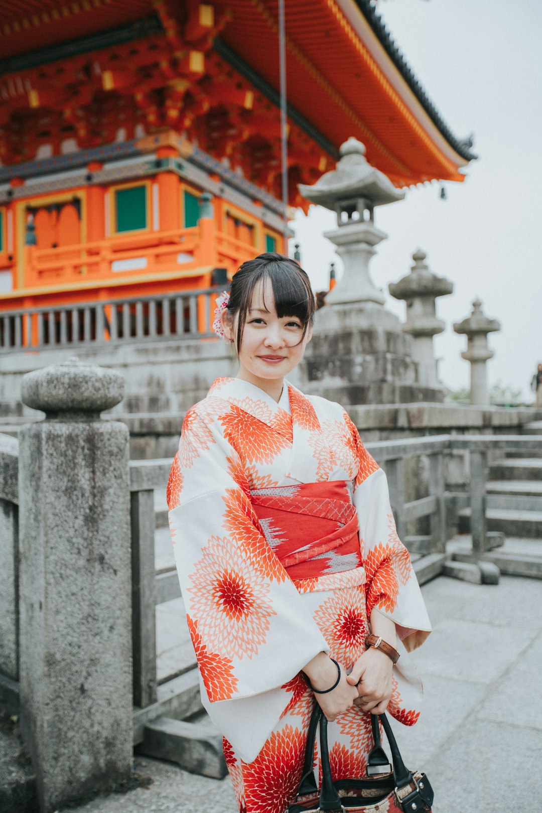 woman in white and red kimono standing near white concrete building during daytime