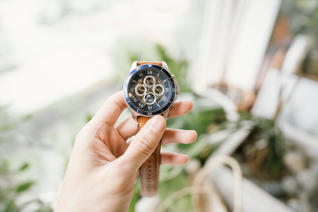 person holding orange and black chronograph watch