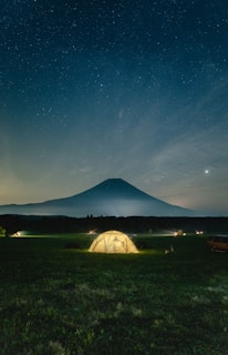 Nighttime camp scene with peakperformancce gear laid out beside a glowing tent.