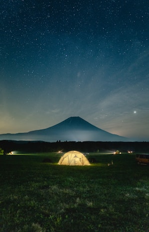 Nighttime camp scene with peakperformancce gear laid out beside a glowing tent.