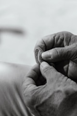 Close-up of hands exchanging an antique coin during a transaction.