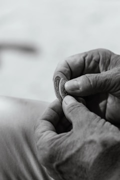 Close-up of hands exchanging an antique coin during a transaction.