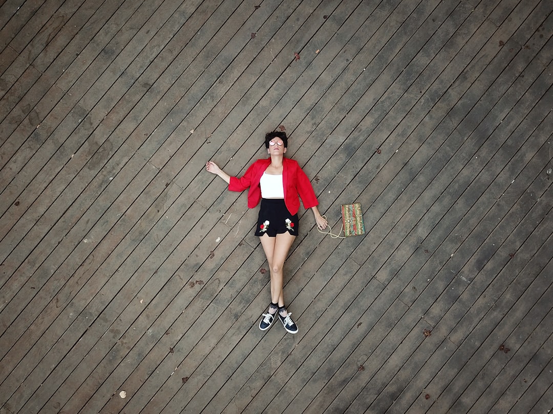 woman in red t-shirt and black shorts standing on brown wooden floor