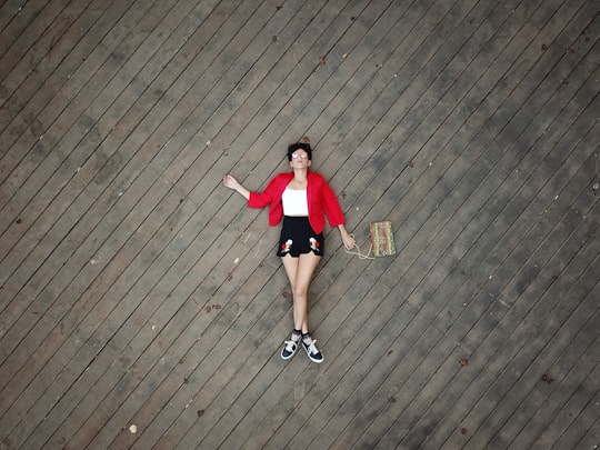 woman in red t-shirt and black shorts standing on brown wooden floor in Haifa Israel