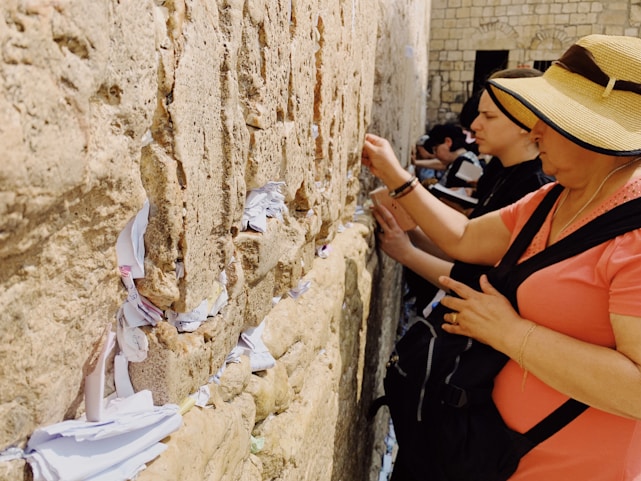 A serene photo of the ancient Western Wall bathed in soft morning light, with a hand gently placing a note in a crack.