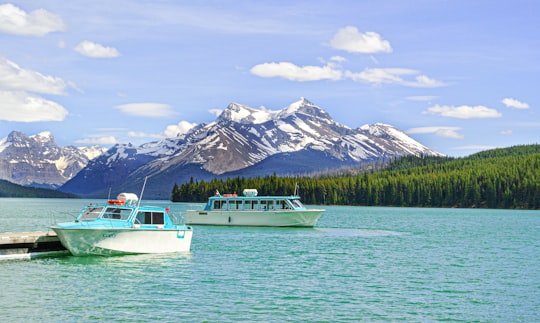 white boat on body of water near mountain during daytime in Jasper National Park Canada