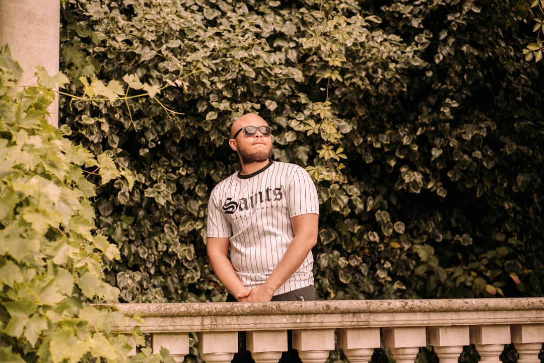 man in white crew neck t-shirt standing on brown wooden bridge