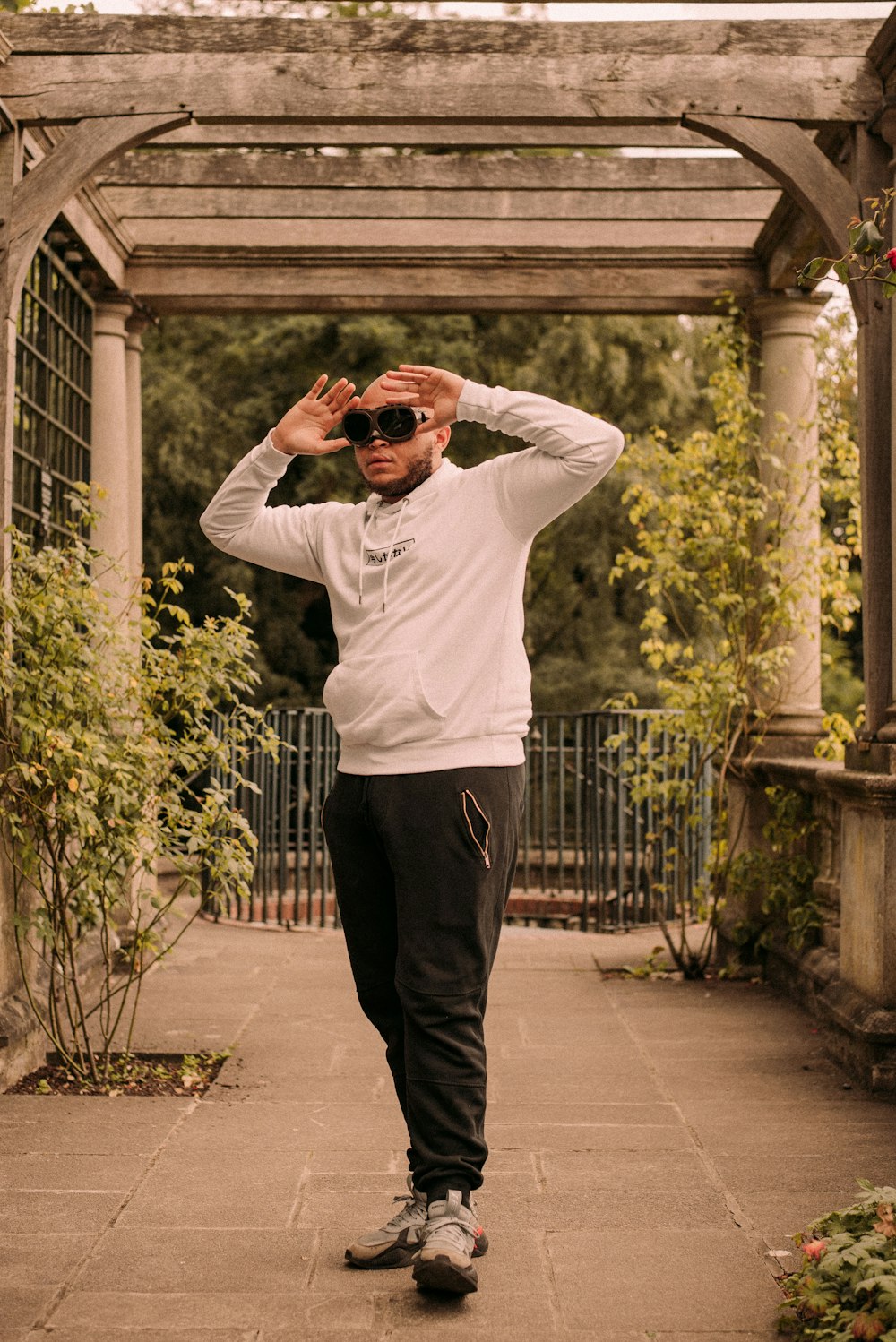 man in white long sleeve shirt and black pants standing on gray concrete floor during daytime