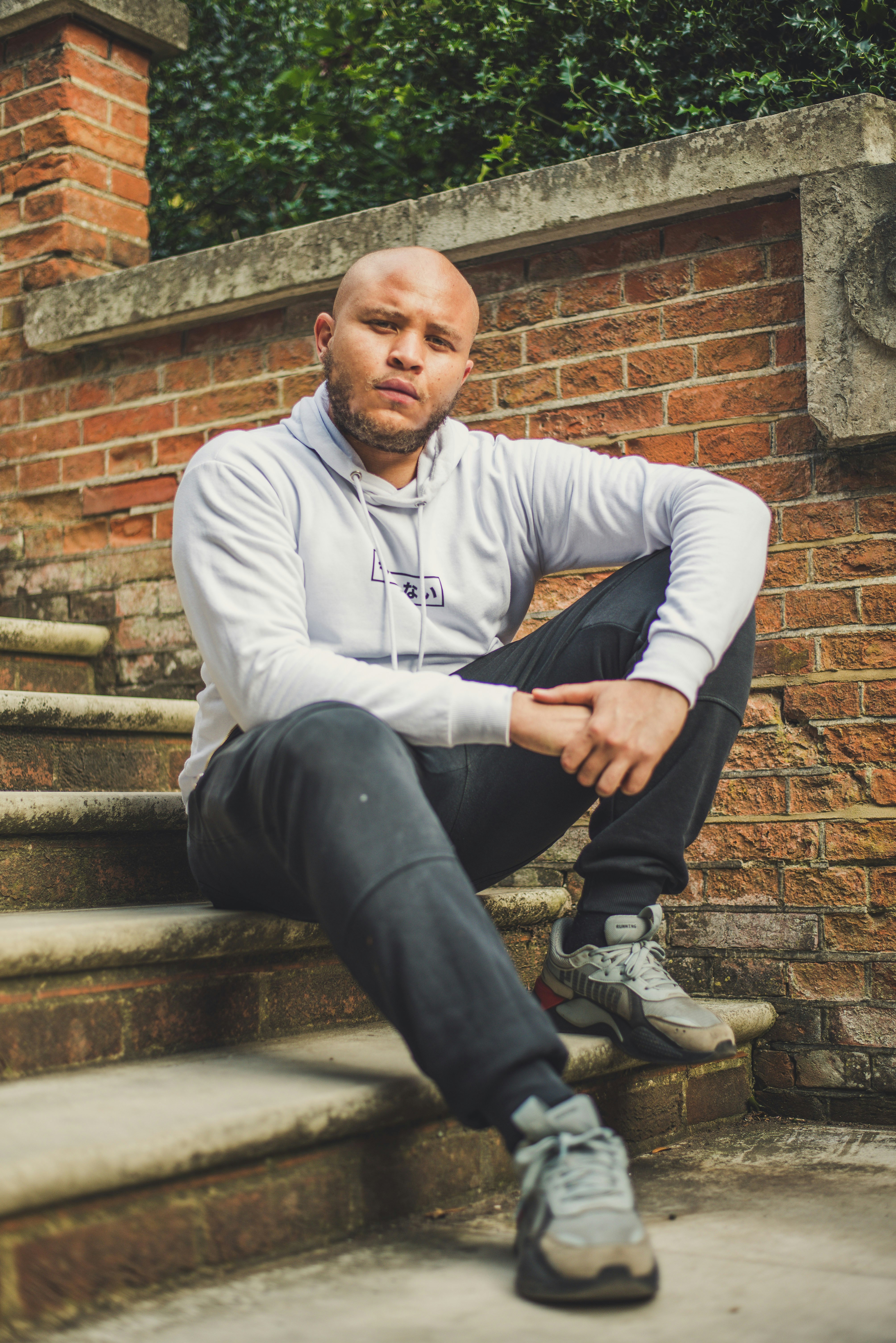 man in white long sleeve shirt and blue denim jeans sitting on brown concrete stairs