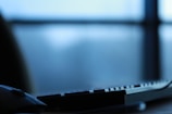 Close-up of hands typing on a keyboard with soft morning light filtering through blinds.