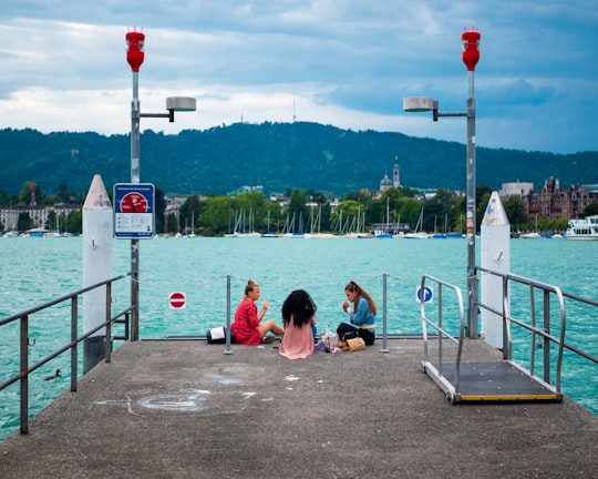 3 women sitting on the beach during daytime in Zürich Switzerland