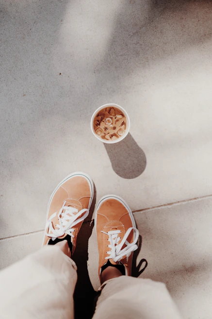 A pair of Chillshoe sneakers casually placed next to a coffee cup on a cozy table