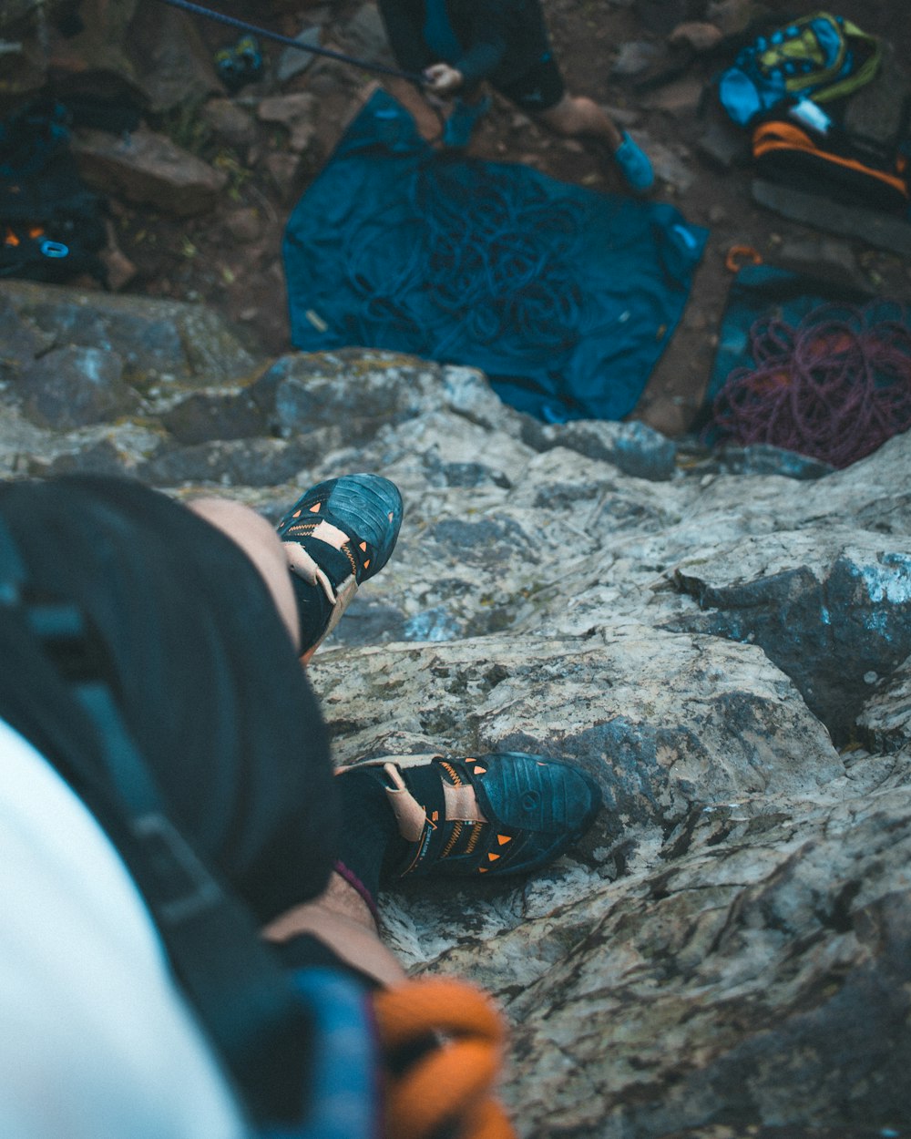 person in black and blue hiking shoes standing on gray rock