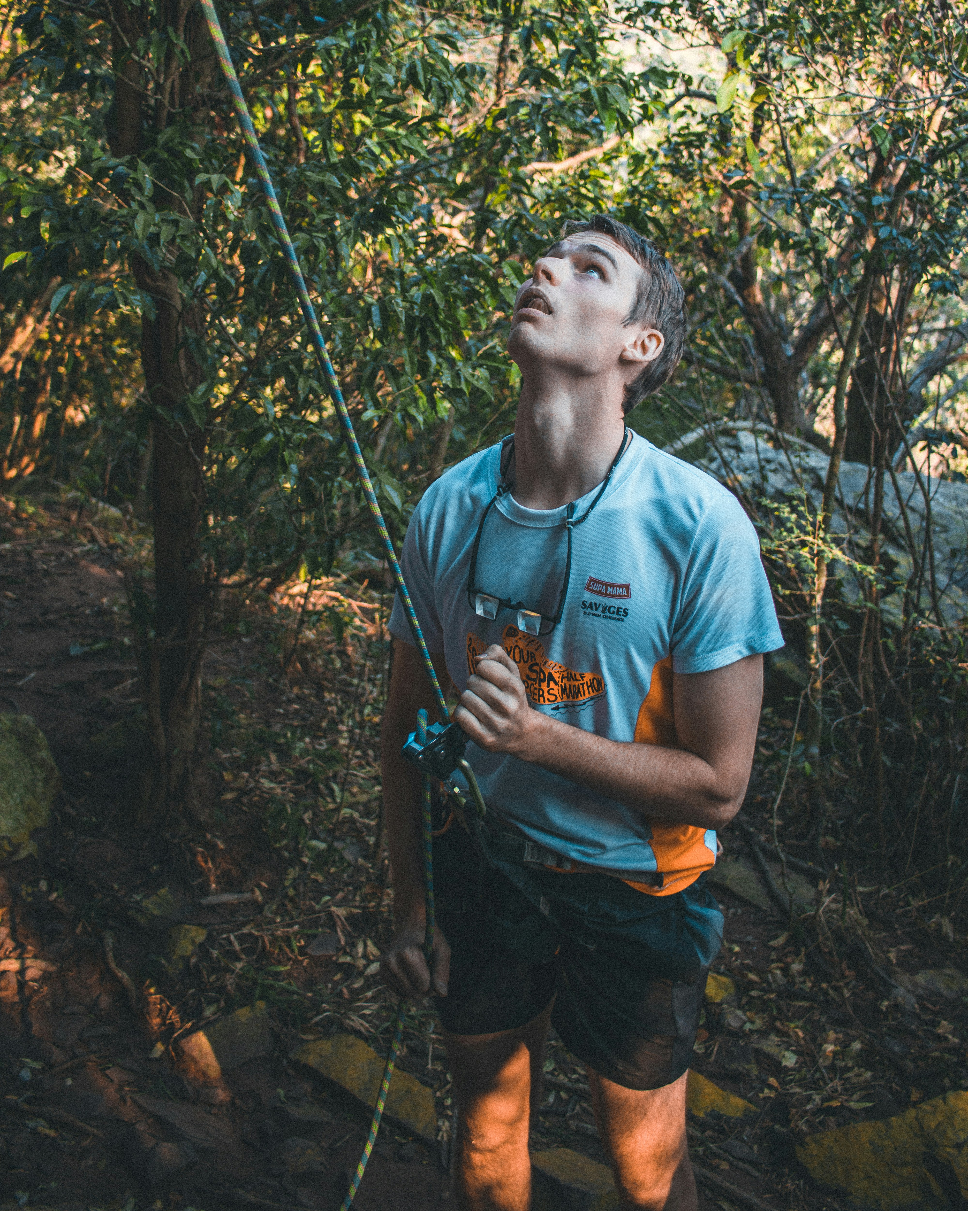 Hombre con camiseta azul de cuello redondo y pantalones cargo marrones sosteniendo una cuerda negra