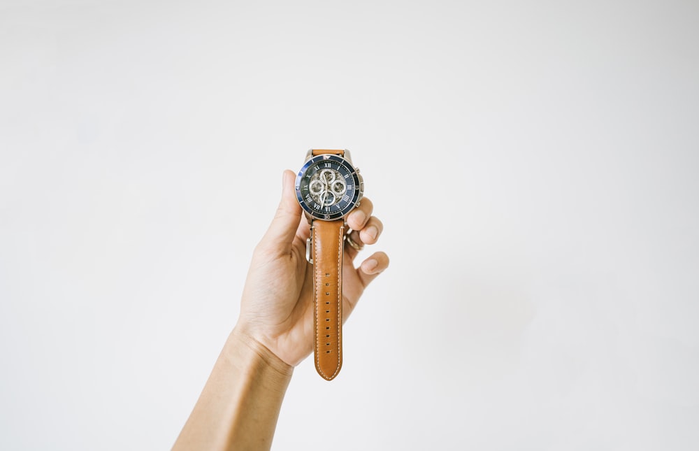 person holding brown and black chronograph watch