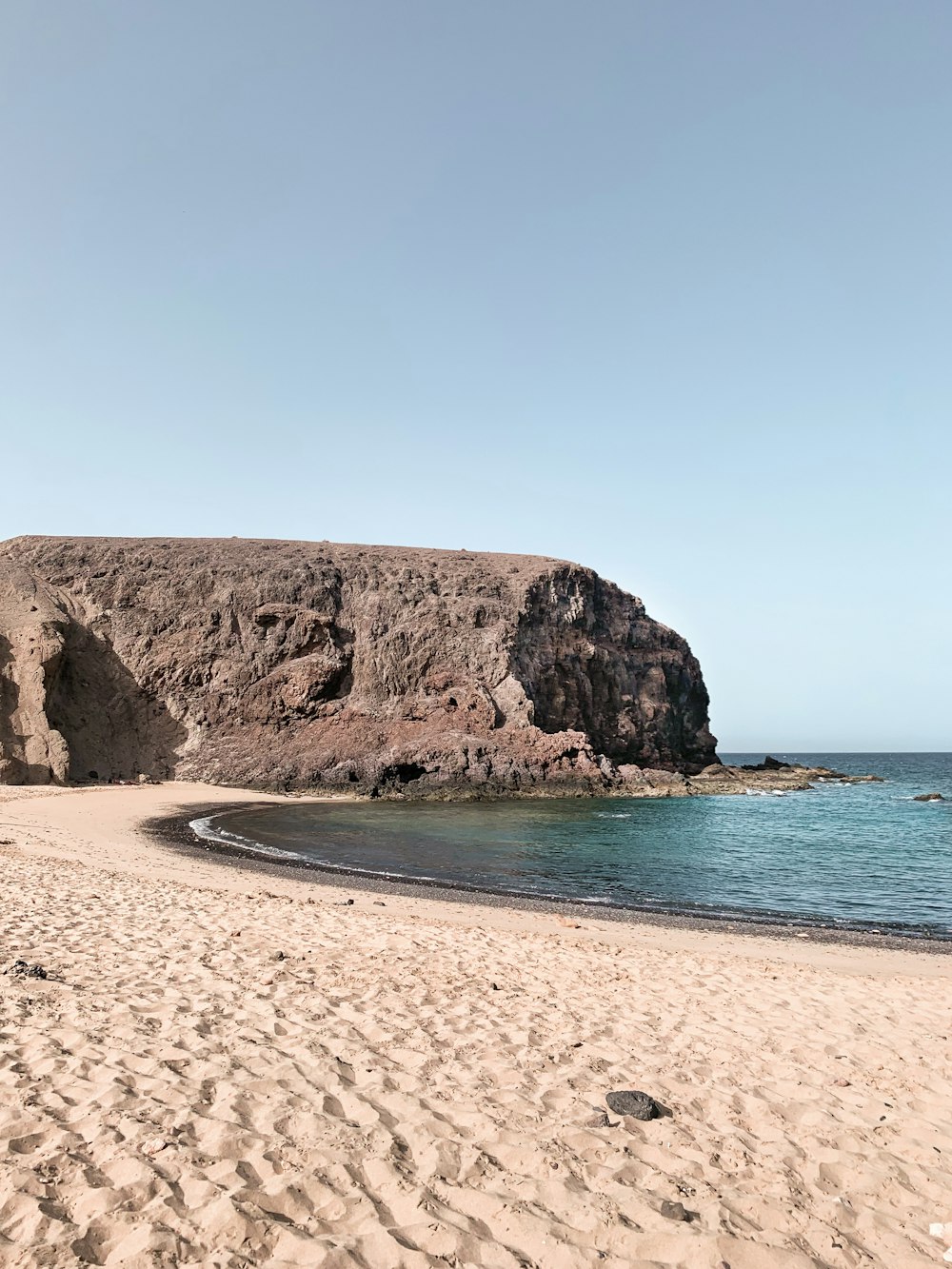 Braune Felsformation auf blauem Meer unter blauem Himmel tagsüber